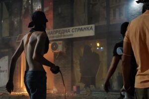 Valjevo, 16. avgusta 2025. - Ucesnici protesta u Valjevu razbijaju prostorije SNS u Valjevu i bacaju baklje i petarde. Stakla na prostrojama su potpuno razbijena, prostorije su potpuno demolirane, a iz njih izlazi crni dim. Do prostorija SNS stigla su vatrogasna vozila. Iznad stranackih prostorija SNS se nalaze stanovi. Kod prostorija SNS nema pripadnika policije. Prostorije SNS razbijaju ucesnici protesta sa fantomkama na licu. FOTO TANJUG/ VLADIMIR PORCIC/ bg